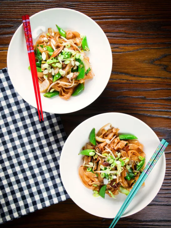 Overhead ho fun noodles stir fry with bean sprouts, shiitake mushrooms and sugar snap peas.
