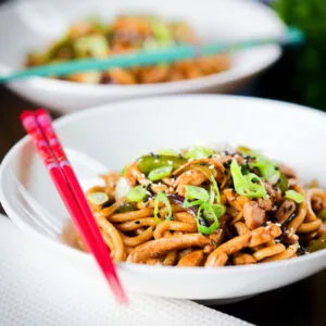 Teriyaki chicken stir fry with udon noodles garnished with spring onions and sesame seeds.