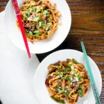 Overhead stir fried teriyaki chicken noodles with spring onions and sesame seeds.