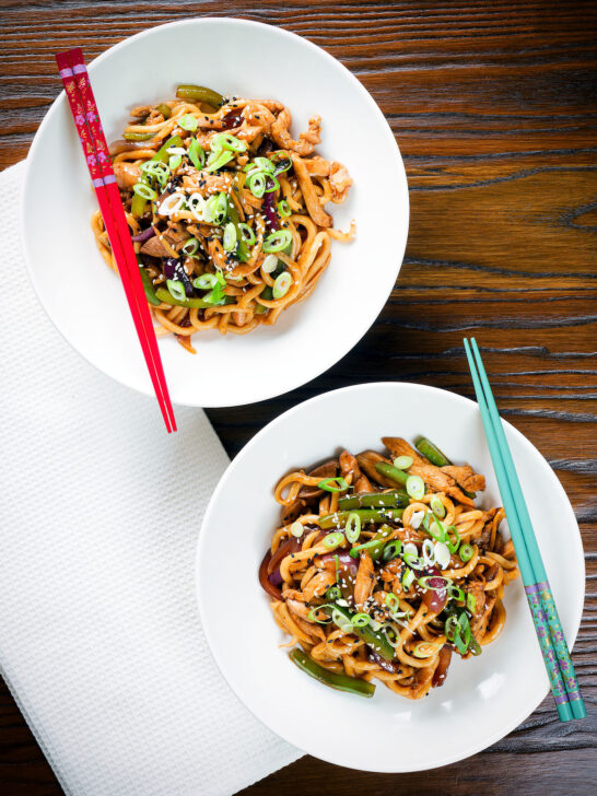 Overhead stir fried teriyaki chicken noodles with spring onions and sesame seeds.
