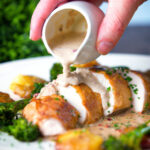 Roasted chicken breast with in peppercorn sauce with extra sauce poured over with broccoli and potatoes.
