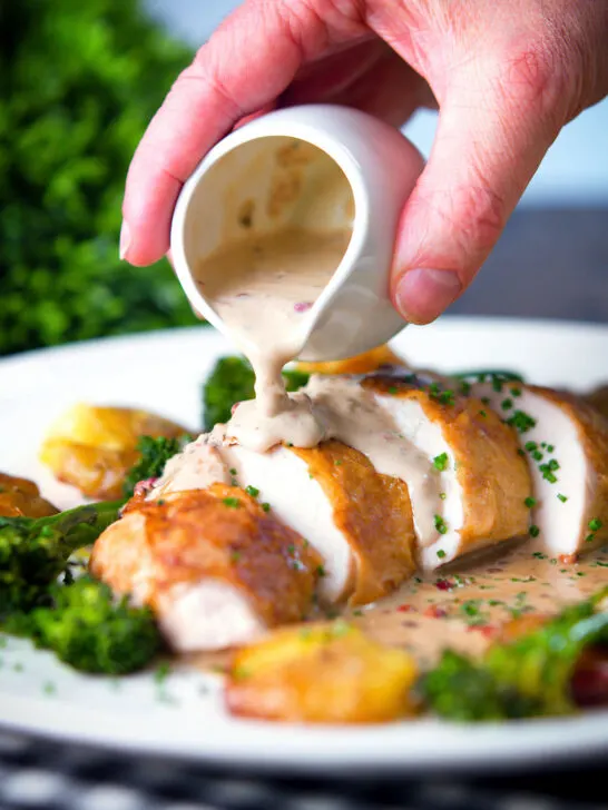 Roasted chicken breast with in peppercorn sauce with extra sauce poured over with broccoli and potatoes.