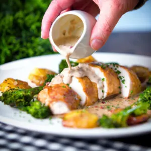 Roasted chicken breast with in peppercorn sauce with extra sauce poured over with broccoli and potatoes.
