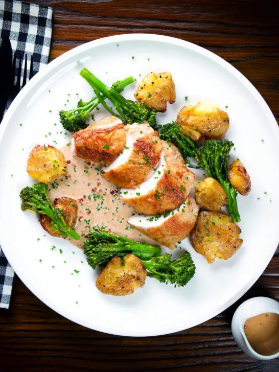 Overhead chicken breast (roasted on the crown) in peppercorn sauce, smashed potatoes and broccoli.