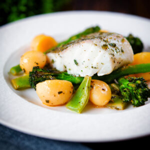 Herby cod traybake with tinned potatoes, tenderstem broccoli and runner beans