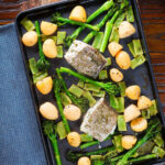 Overhead cod traybake with potatoes, broccoli and runner beans on a sheet pan.
