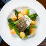 Overhead cod traybake with potatoes, broccoli and runner beans cooked in a herby olive oil.