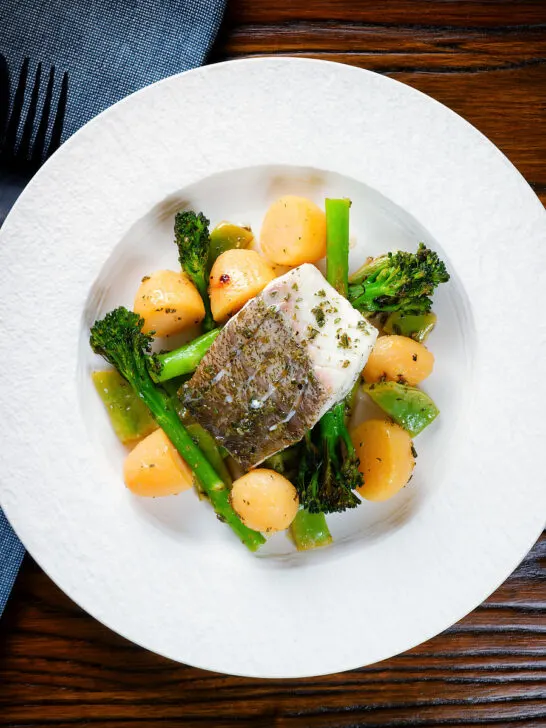 Overhead cod traybake with potatoes, broccoli and runner beans cooked in a herby olive oil.