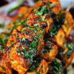Close-up paneer tikka kebabs served with homemade chapatis, onion salad and mango chutney.