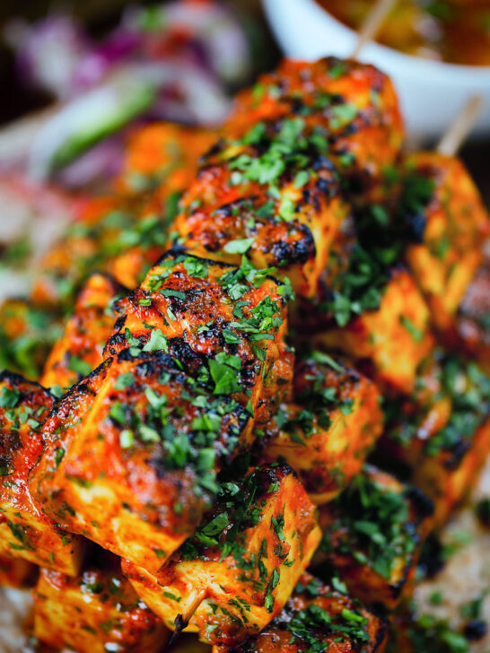 Close-up paneer tikka kebabs served with homemade chapatis, onion salad and mango chutney.