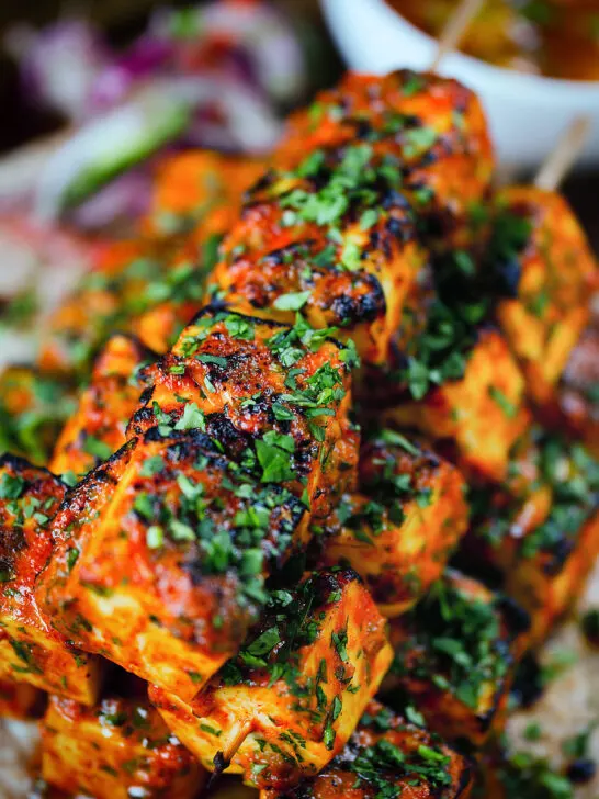 Close-up paneer tikka kebabs served with homemade chapatis, onion salad and mango chutney.