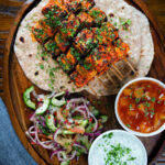Overhead paneer tikka kebabs served with chapatis, onion salad, raita and mango chutney.