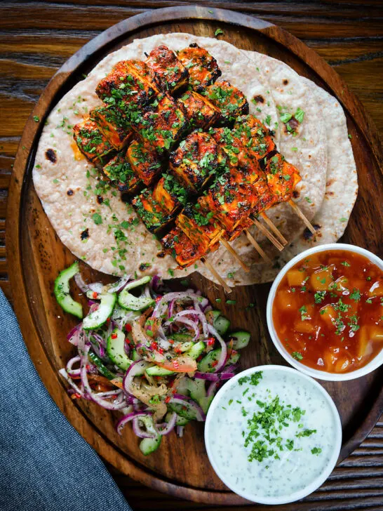 Overhead paneer tikka kebabs served with chapatis, onion salad, raita and mango chutney.