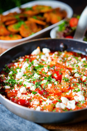 Greek prawn (shrimp) saganaki with feta cheese served with potatoes and salad.