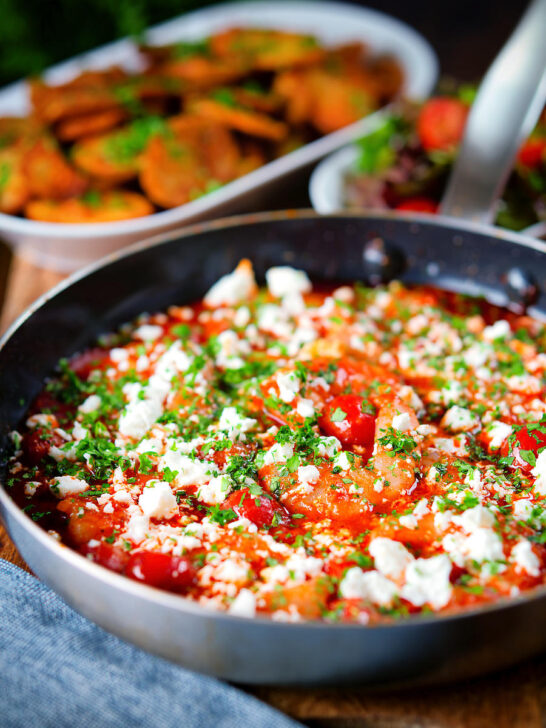 Greek prawn (shrimp) saganaki with feta cheese served with potatoes and salad.