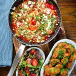 Overhead Greek prawn (shrimp) saganaki with feta cheese served with potatoes and salad.