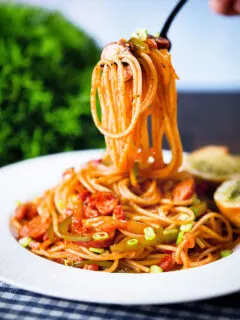 Spaghetti napolitan a Japanese tomato ketchup pasta with sausage and bacon being eaten with a fork.