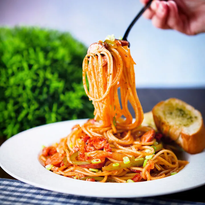 Spaghetti napolitan a Japanese tomato ketchup pasta with sausage and bacon being eaten with a fork.