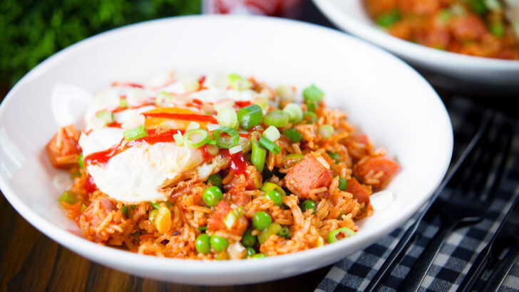 Spicy Spam fried rice with kimchi and garden peas, served with a fried egg and Sriracha sauce.