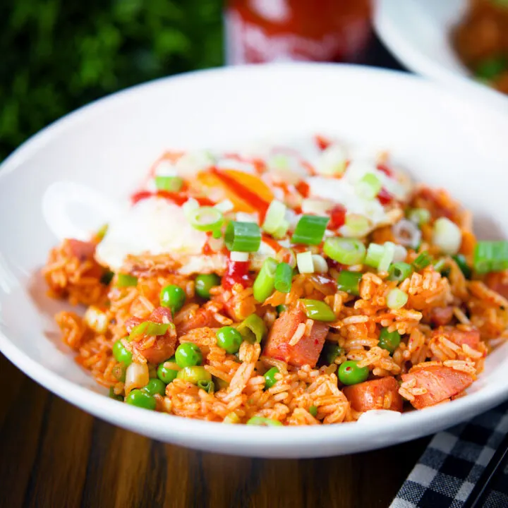 Spicy Spam fried rice with kimchi and garden peas, served with a fried egg and Sriracha sauce.