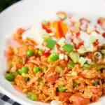 Spicy Spam fried rice with kimchi and peas, served with a fried egg and Sriracha sauce.