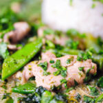 Close-up herby Thai green pork curry with sugar snap peas and jasmine rice.