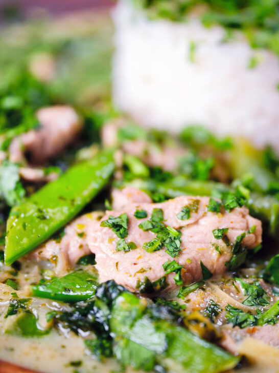 Close-up herby Thai green pork curry with sugar snap peas and jasmine rice.