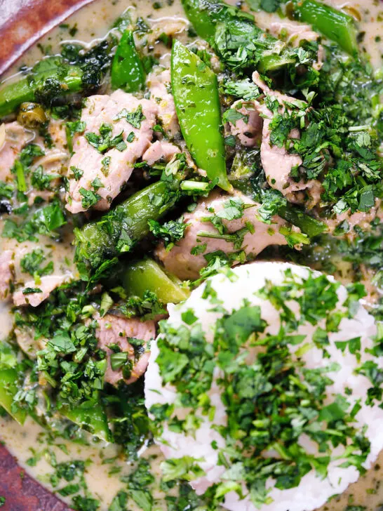 Close-up overhead herby Thai green pork curry with sugar snap peas and jasmine rice.