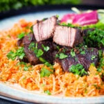 Afelia or Cypriot pork braised in red wine and coriander seeds showing meat texture served with pourgouri.