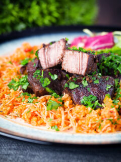 Afelia or Cypriot pork braised in red wine and coriander seeds showing meat texture served with pourgouri.