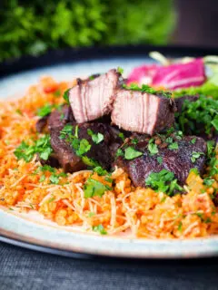 Afelia or Cypriot pork braised in red wine and coriander seeds showing meat texture served with pourgouri.