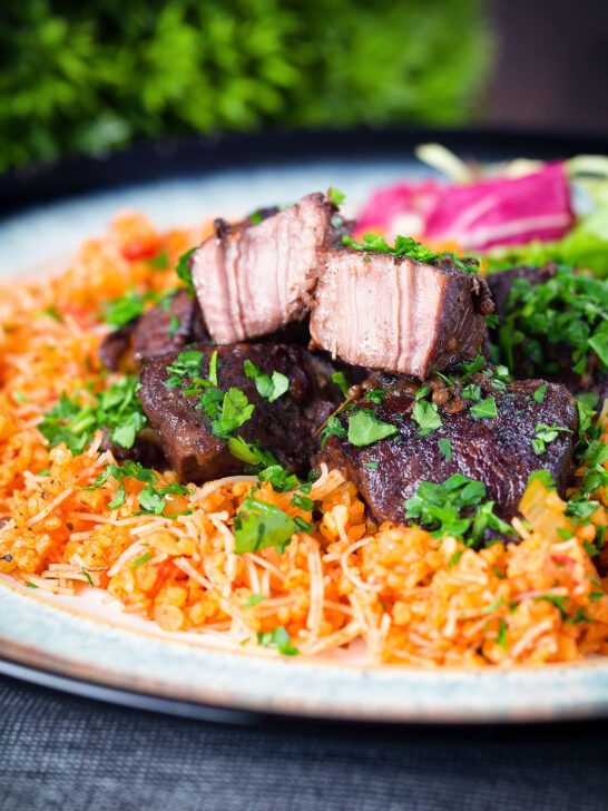 Afelia or Cypriot pork braised in red wine and coriander seeds showing meat texture served with pourgouri.