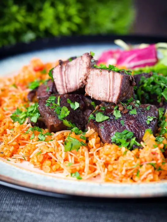 Afelia or Cypriot pork braised in red wine and coriander seeds showing meat texture served with pourgouri.