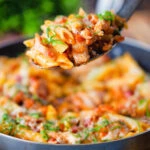 BBQ chicken and bacon pasta with cheddar cheese being served from a pan.