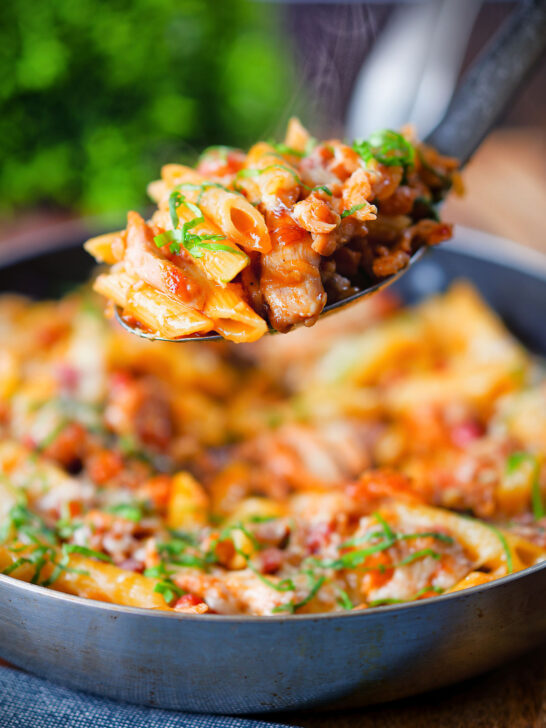 BBQ chicken and bacon pasta with cheddar cheese being served from a pan.