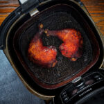Char siu chicken legs in an air fryer basket.
