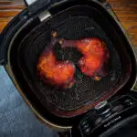 Char siu chicken legs in an air fryer basket.