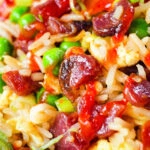 Close-up Chinese sausage (lap cheong) and egg fried rice with garden peas and spring onion.