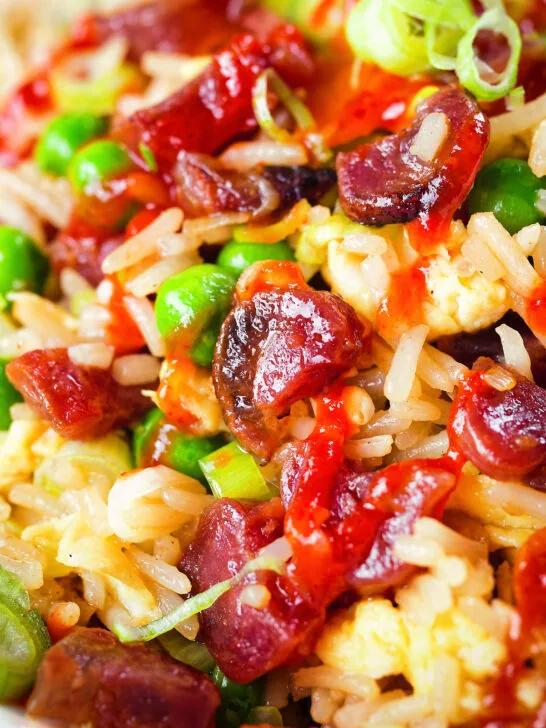 Close-up Chinese sausage (lap cheong) and egg fried rice with garden peas and spring onion.