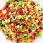 Close-up overhead Chinese sausage (lap cheong) and egg fried rice with garden peas and spring onion.