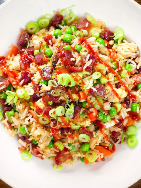 Close-up overhead Chinese sausage (lap cheong) and egg fried rice with garden peas and spring onion.