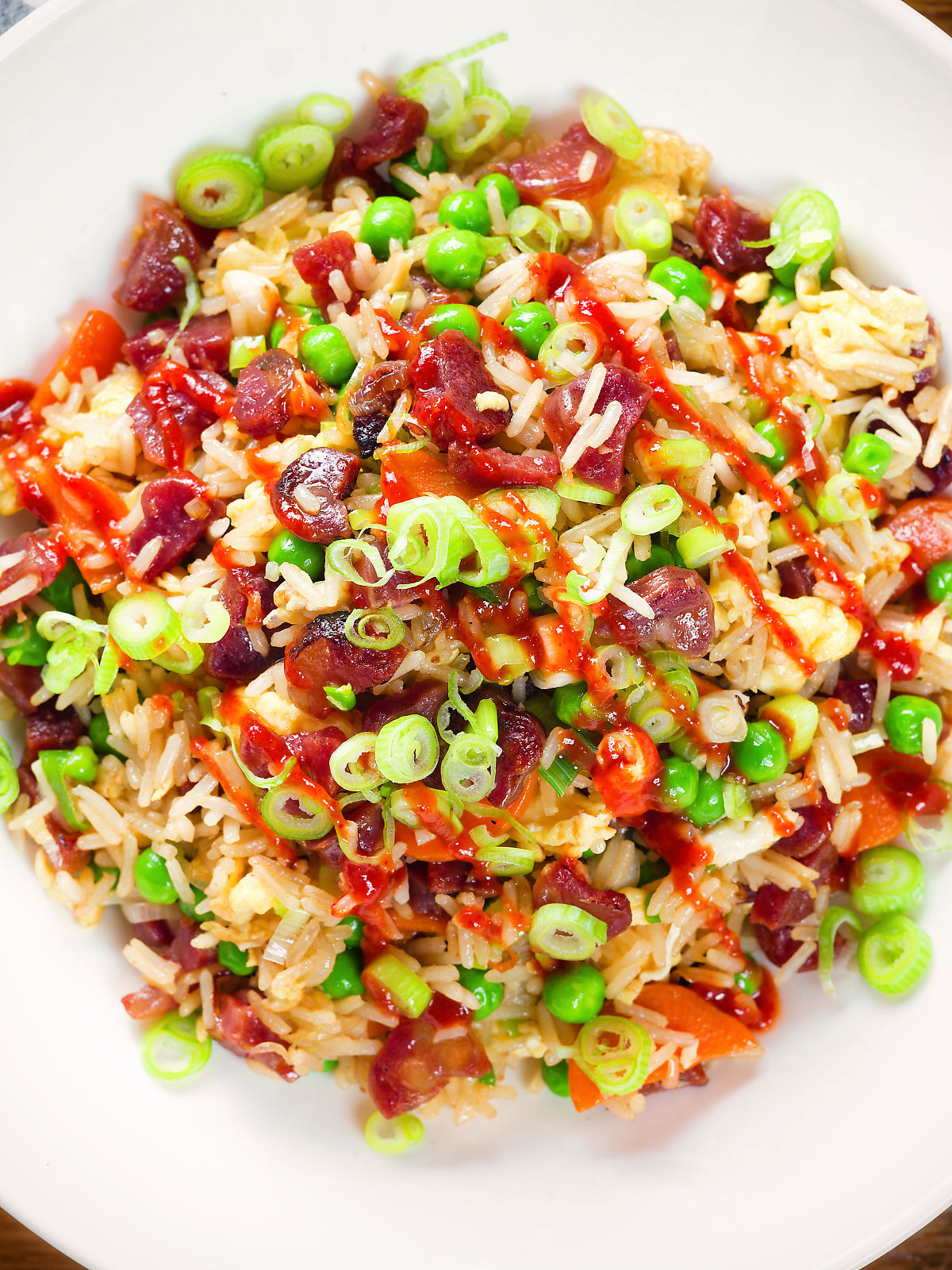 Close-up overhead Chinese sausage (lap cheong) and egg fried rice with garden peas and spring onion.
