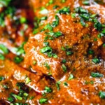 Close-up Goan chicken xacuti curry served with white rice and fresh coriander.