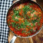 Overhead Goan chicken xacuti curry served in a cooking pan.