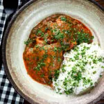 Overhead Goan chicken xacuti curry served with white rice and fresh coriander.
