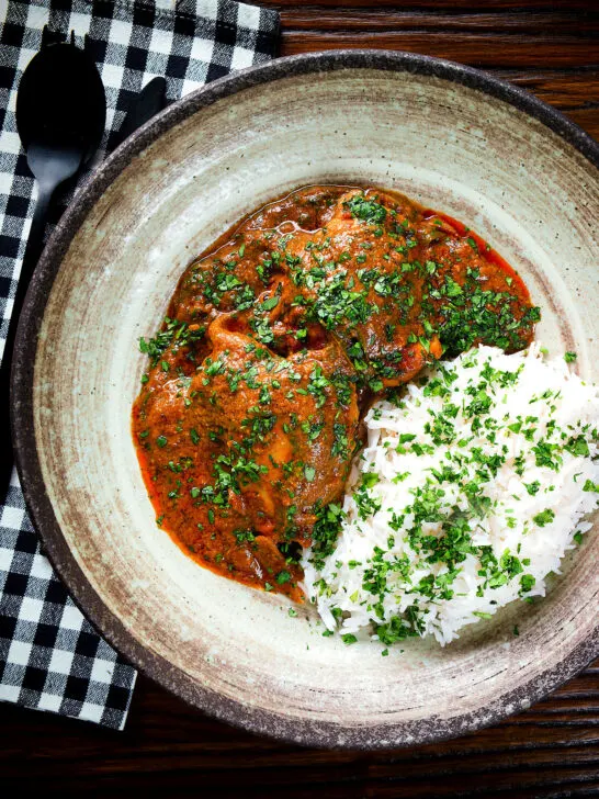 Overhead Goan chicken xacuti curry served with white rice and fresh coriander.