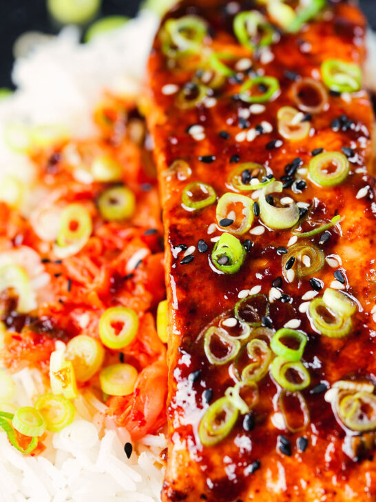 Overhead close-up gochujang and honey glazed salmon fillet served with kimchi and rice.