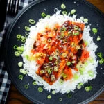 Overhead gochujang and honey glazed salmon fillet served with kimchi and steamed rice.