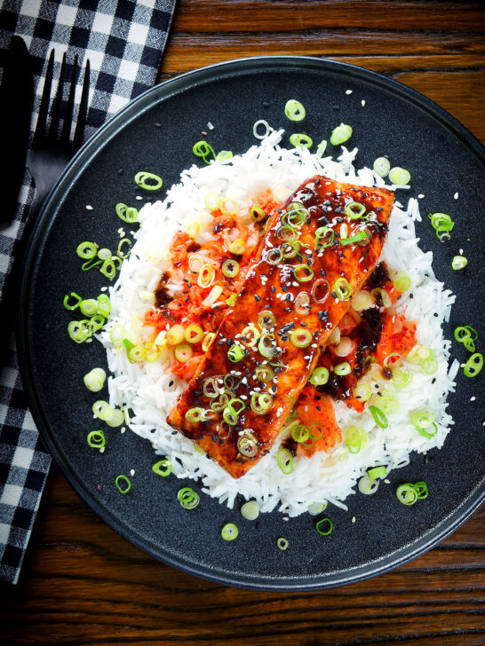 Overhead gochujang and honey glazed salmon fillet served with kimchi and steamed rice.