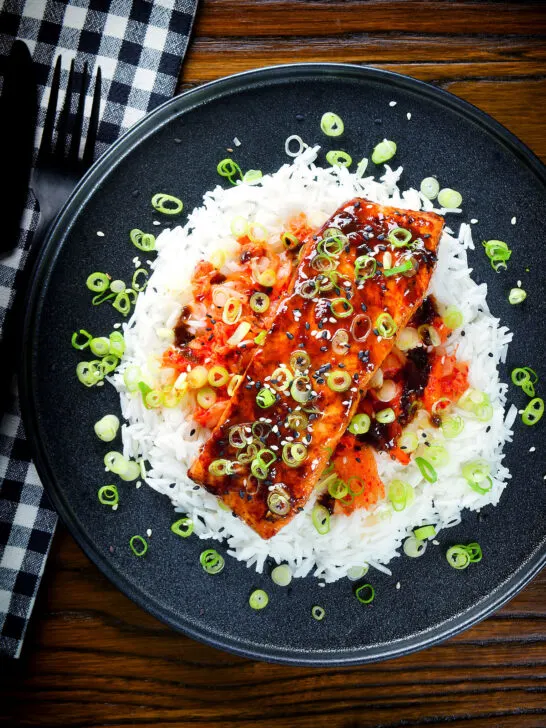 Overhead gochujang and honey glazed salmon fillet served with kimchi and steamed rice.